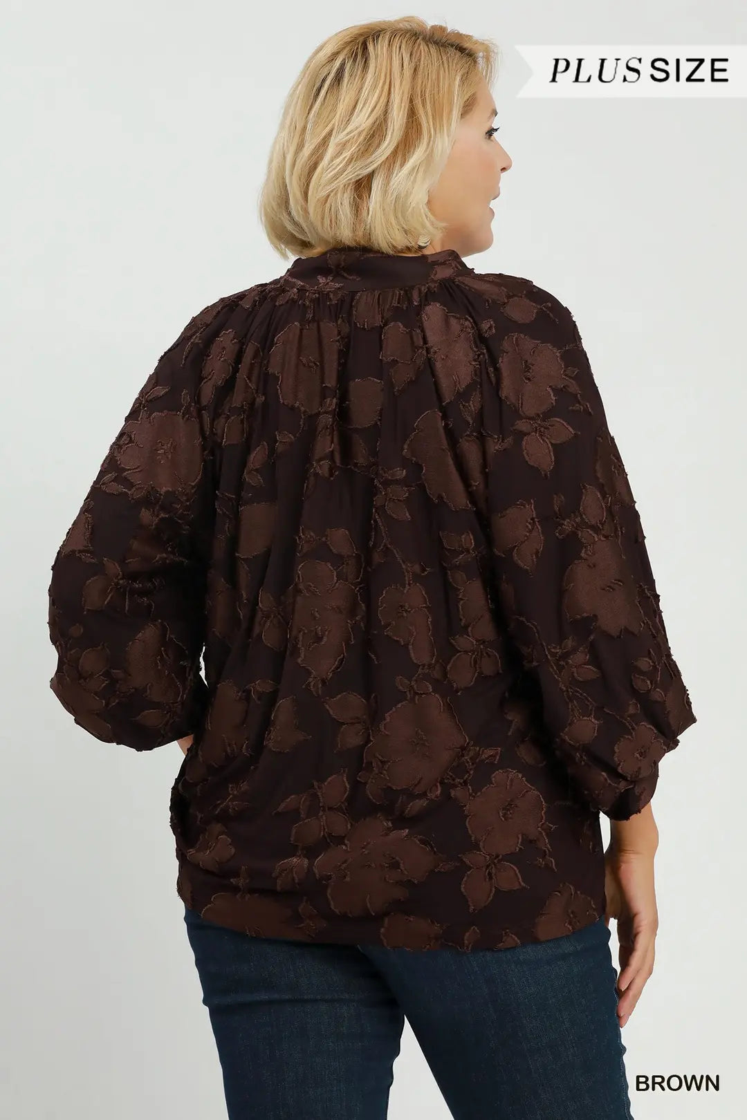 Woman wearing a brown floral patterned blouse on a white background