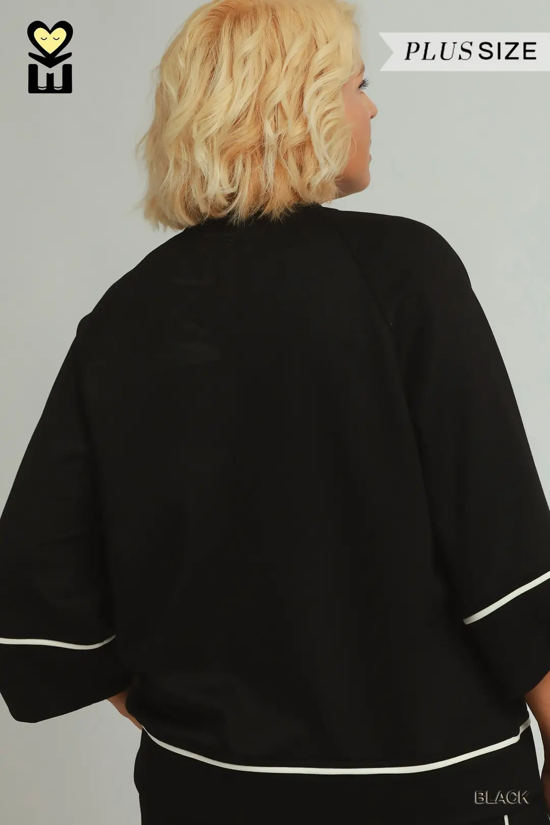 A model wearing a black umgee luxeknit top with white pipping in plus size