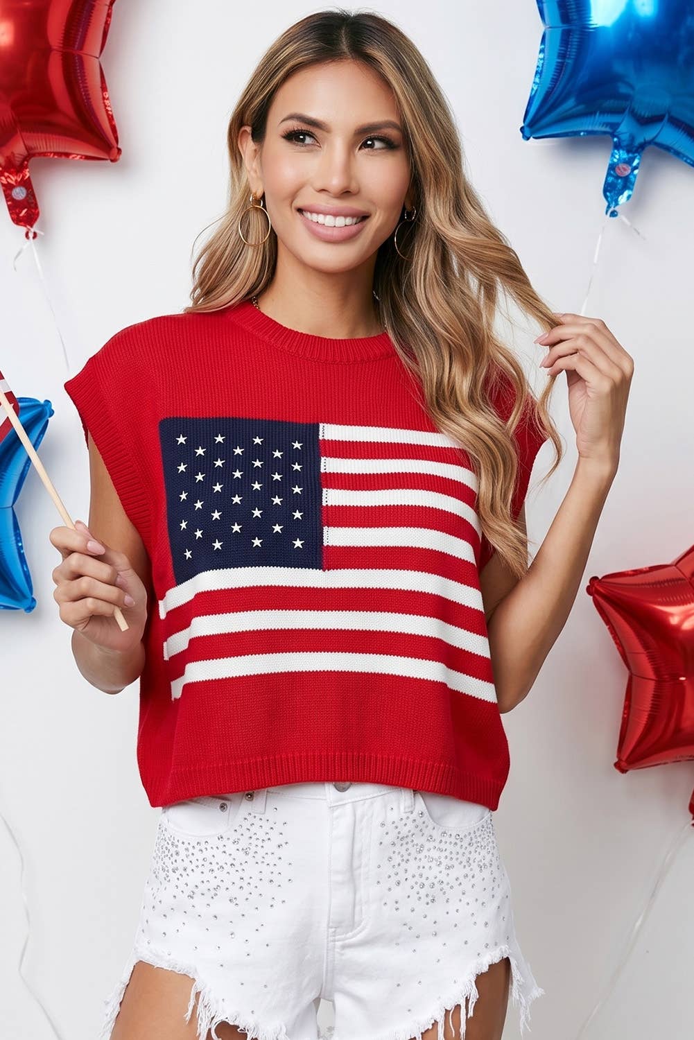 Woman wearing a red sweater with an American flag design, surrounded by colorful balloons.