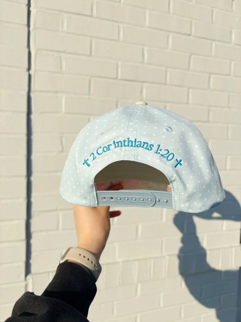 Light blue cap with text held against a light brick wall