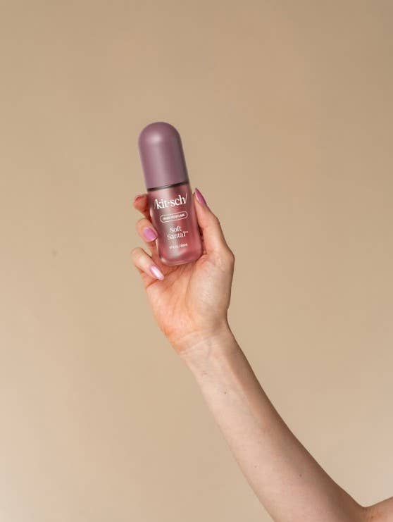 A hand holding a small bottle of bitsch Beauty Glow Serum against a solid beige background.