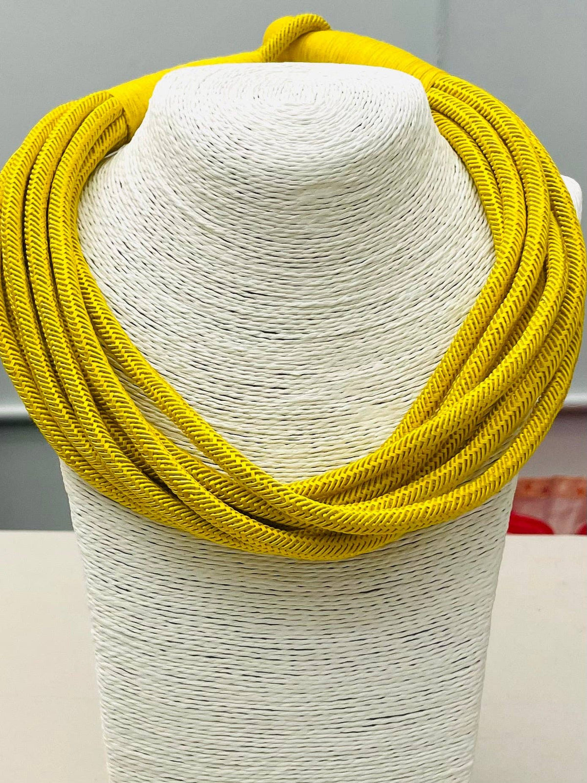 Yellow scarf on a mannequin head against a neutral background