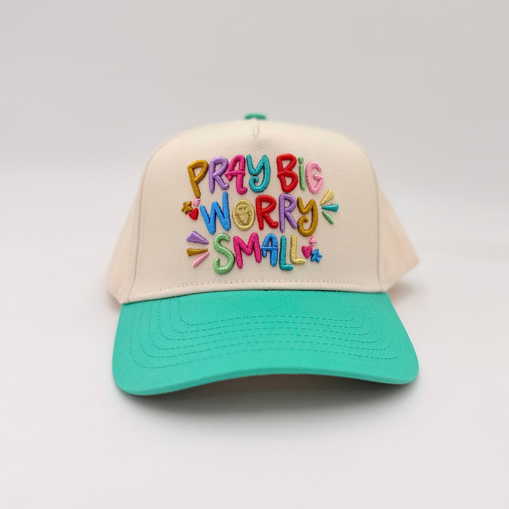 Cap with colorful text 'PRAY BIG WORRY SMALL' on a white background