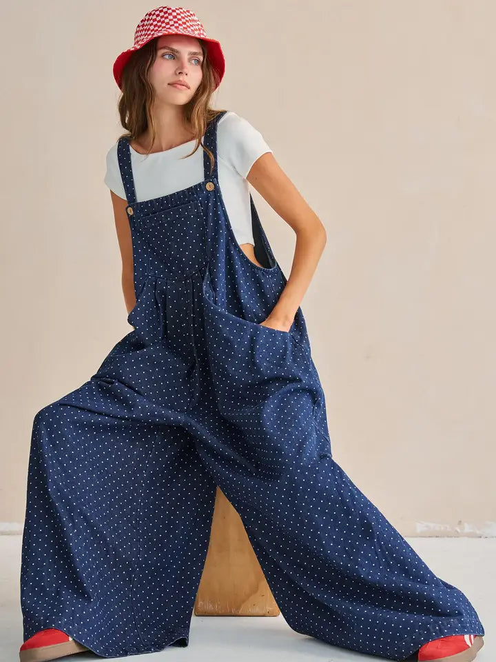 Navy polka dot wide-leg overall jumpsuit, seated pose, side angle
