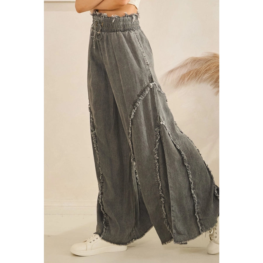 Gray wide-leg jeans with frayed edges worn by a person on a neutral background