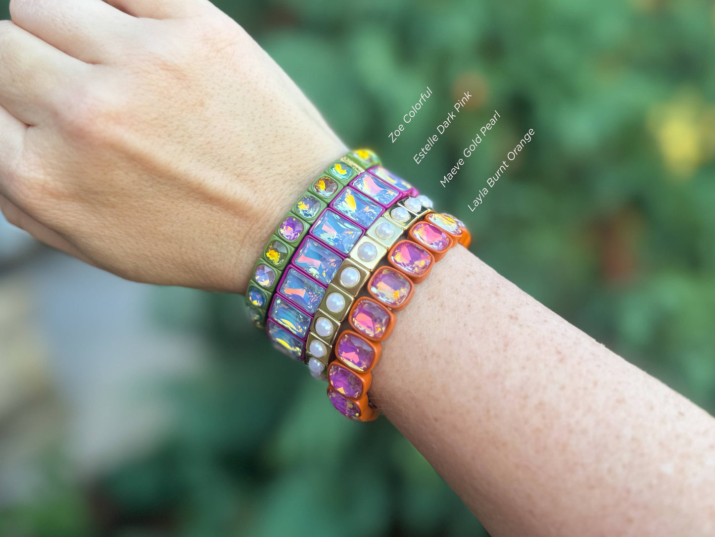 Colorful beaded bracelets on a wrist with a blurred green background