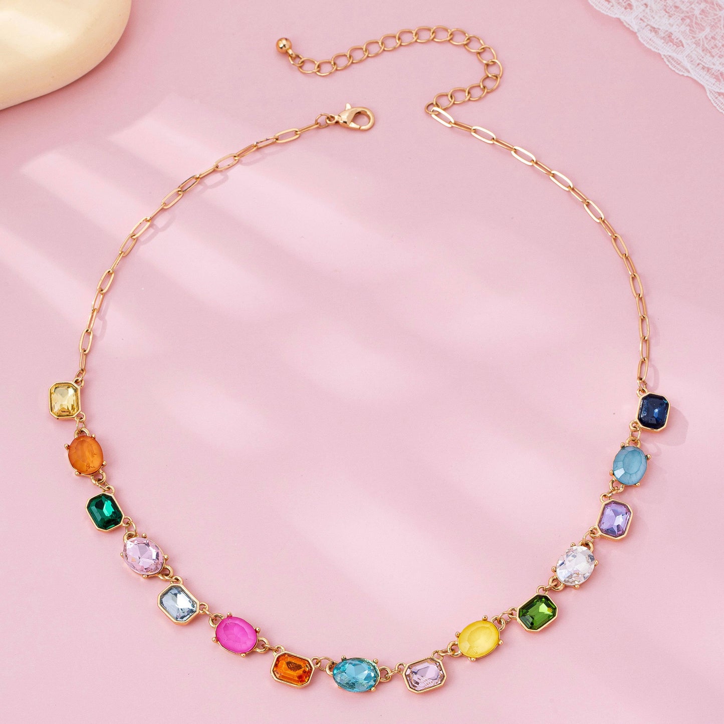 Necklace with colorful gemstones on a pink background
