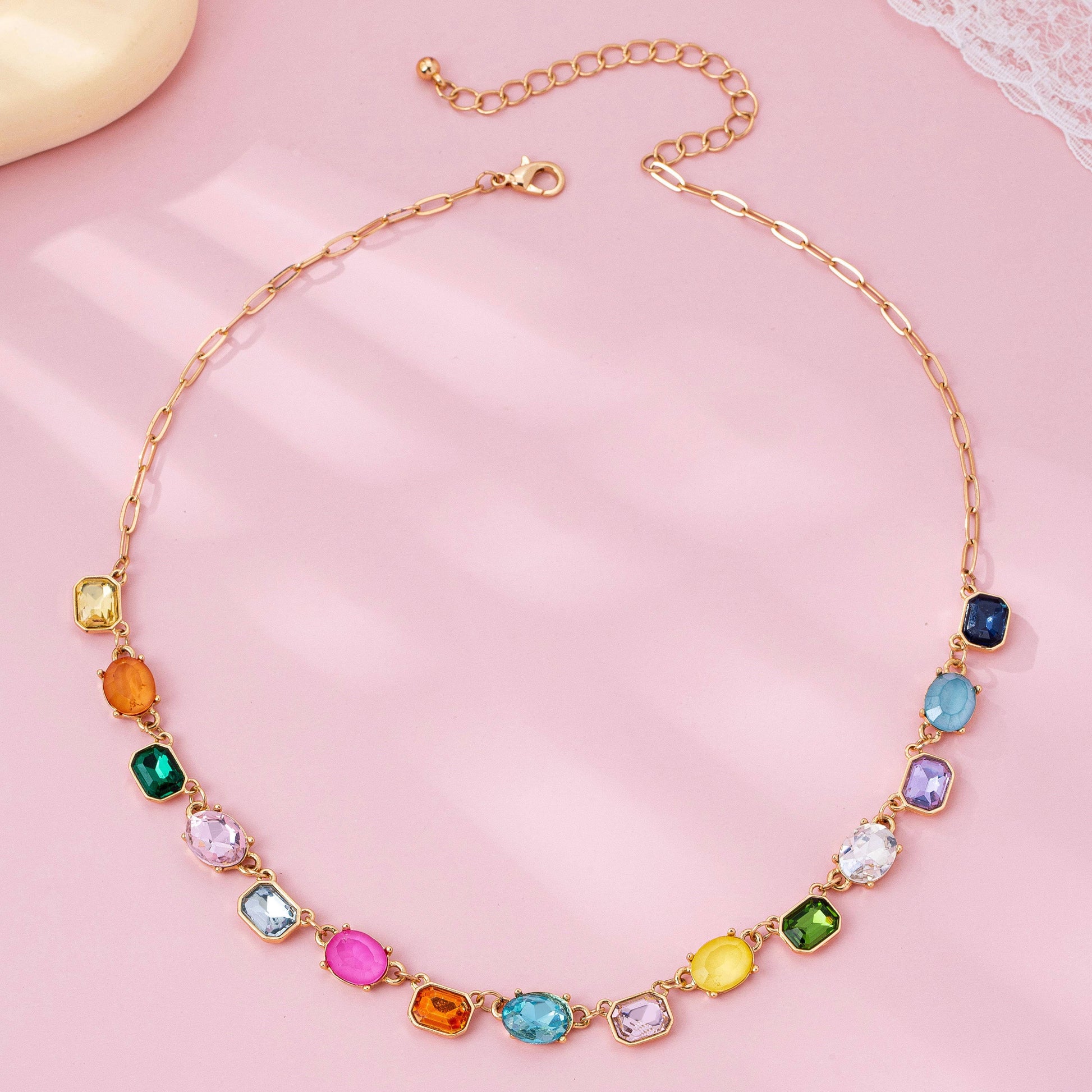 Necklace with colorful gemstones on a pink background
