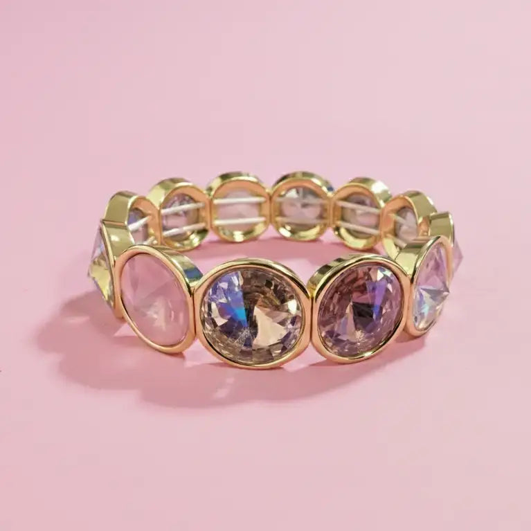 Gold bracelet with clear gemstones on a pink background