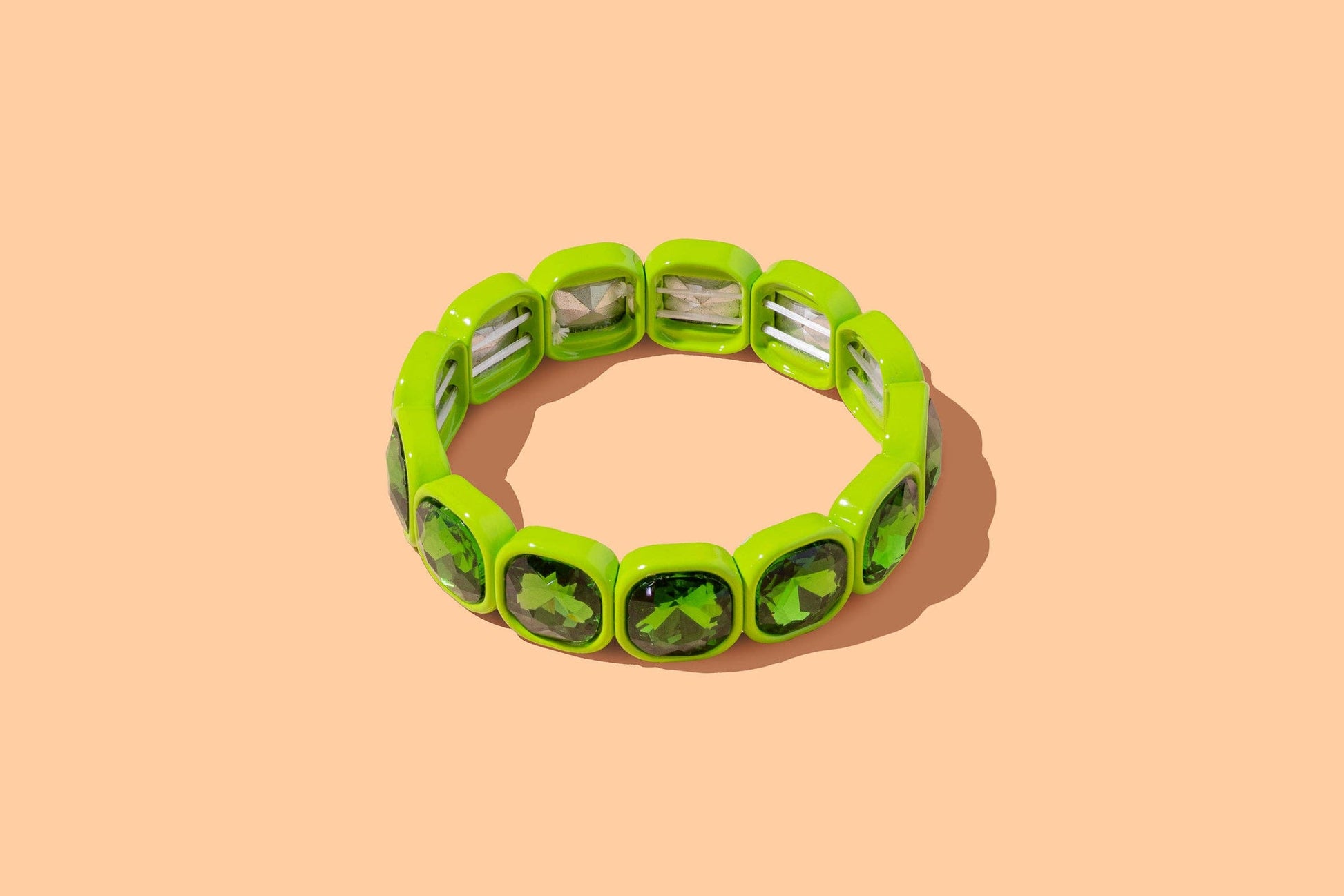 Green bracelet with silver accents on a beige background