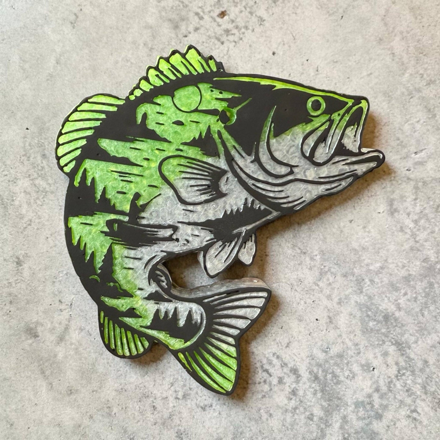 Green and black fish freshie on a concrete surface