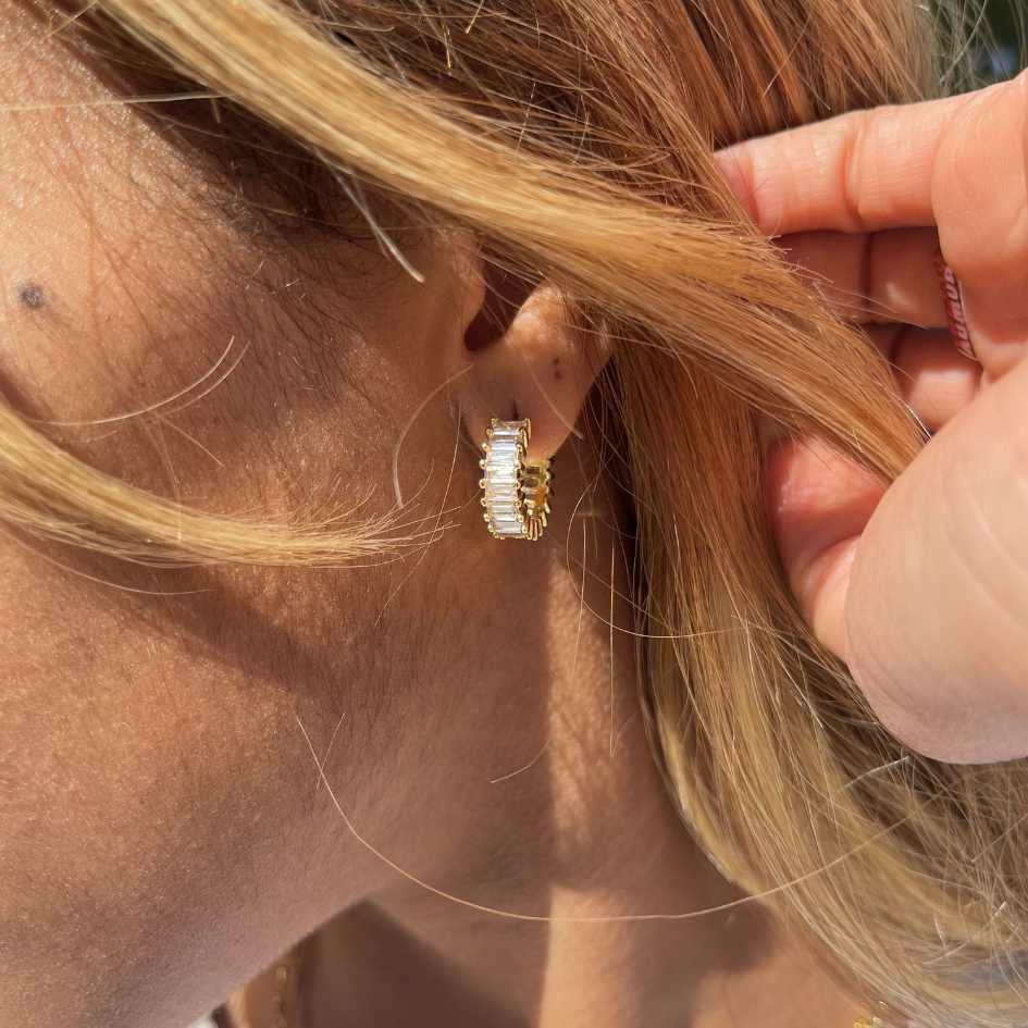 Close-up of a gold earring worn by a person with blonde hair.