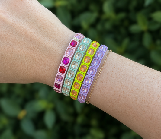 Colorful beaded bracelets on a wrist with a blurred green background