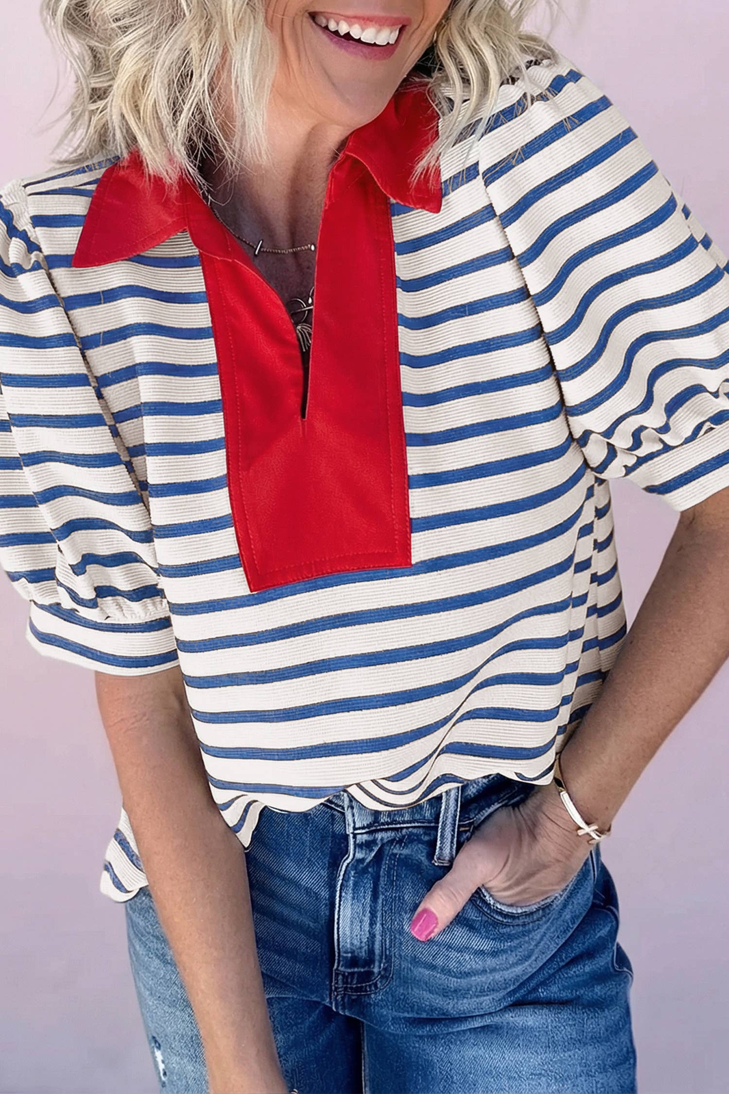 Woman wearing blue and white striped V-neck top with bold red contrast collar and denim jeans