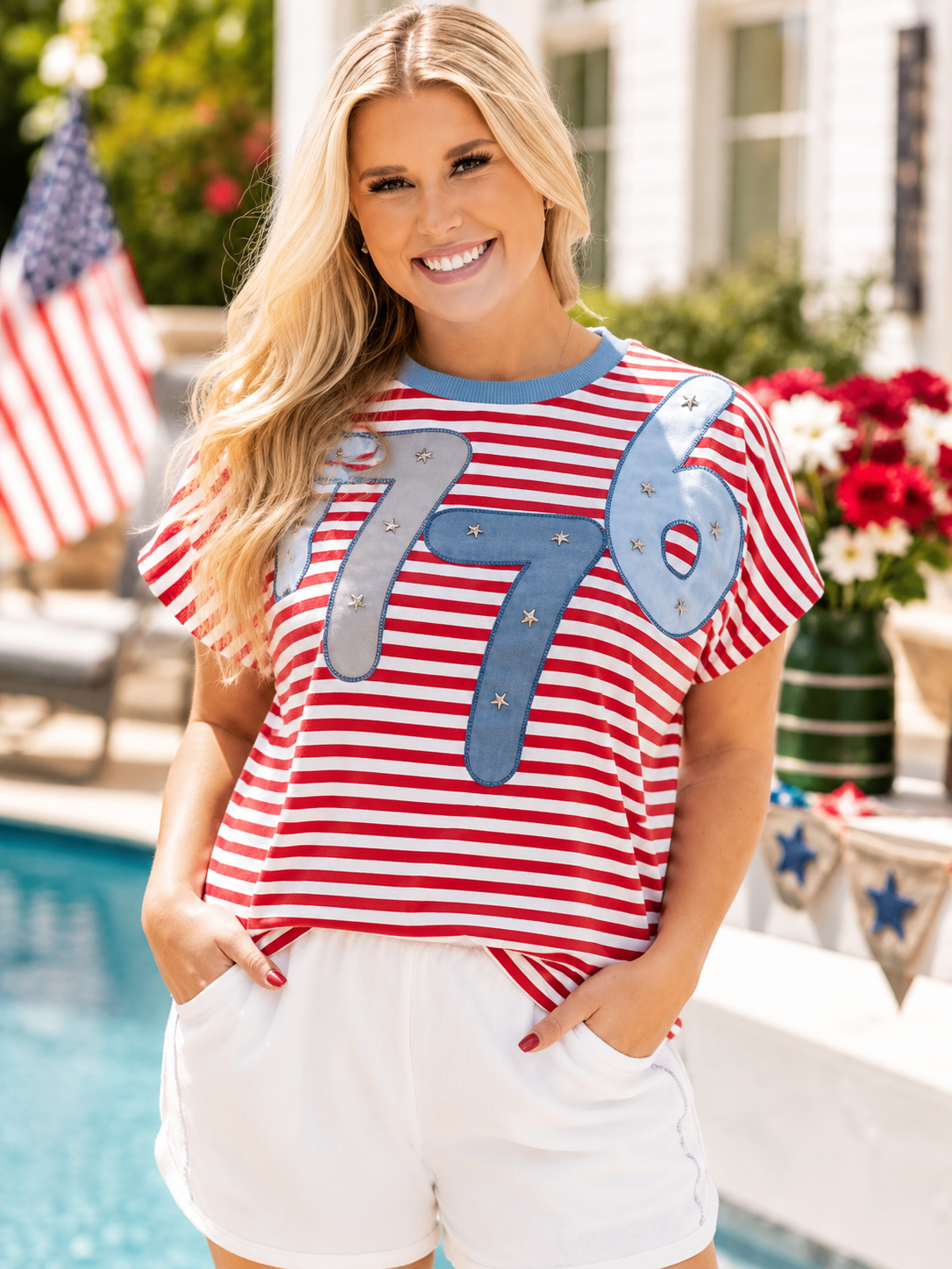 Woman wearing a red and white striped shirt with '1776' and stars, standing by a poolside.