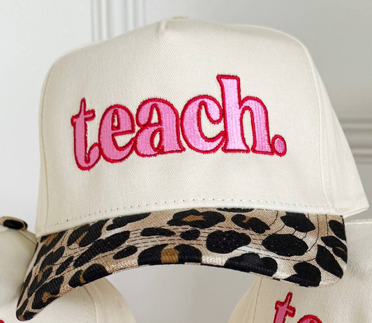 An off-white baseball cap with 'teach.' embroidered in pink on the front, featuring a leopard-print patterned visor.