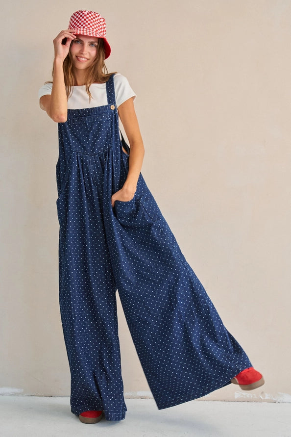 Navy polka dot wide-leg overall jumpsuit, front view with red checkered bucket hat and white tee, red shoes