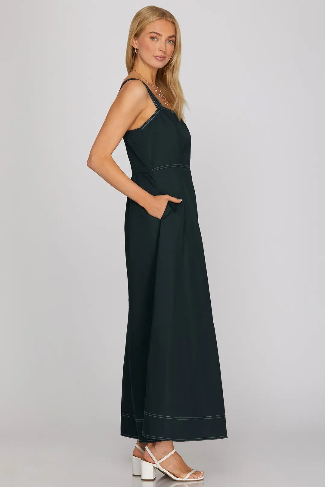 Woman wearing a black sleeveless jumpsuit on a gray background