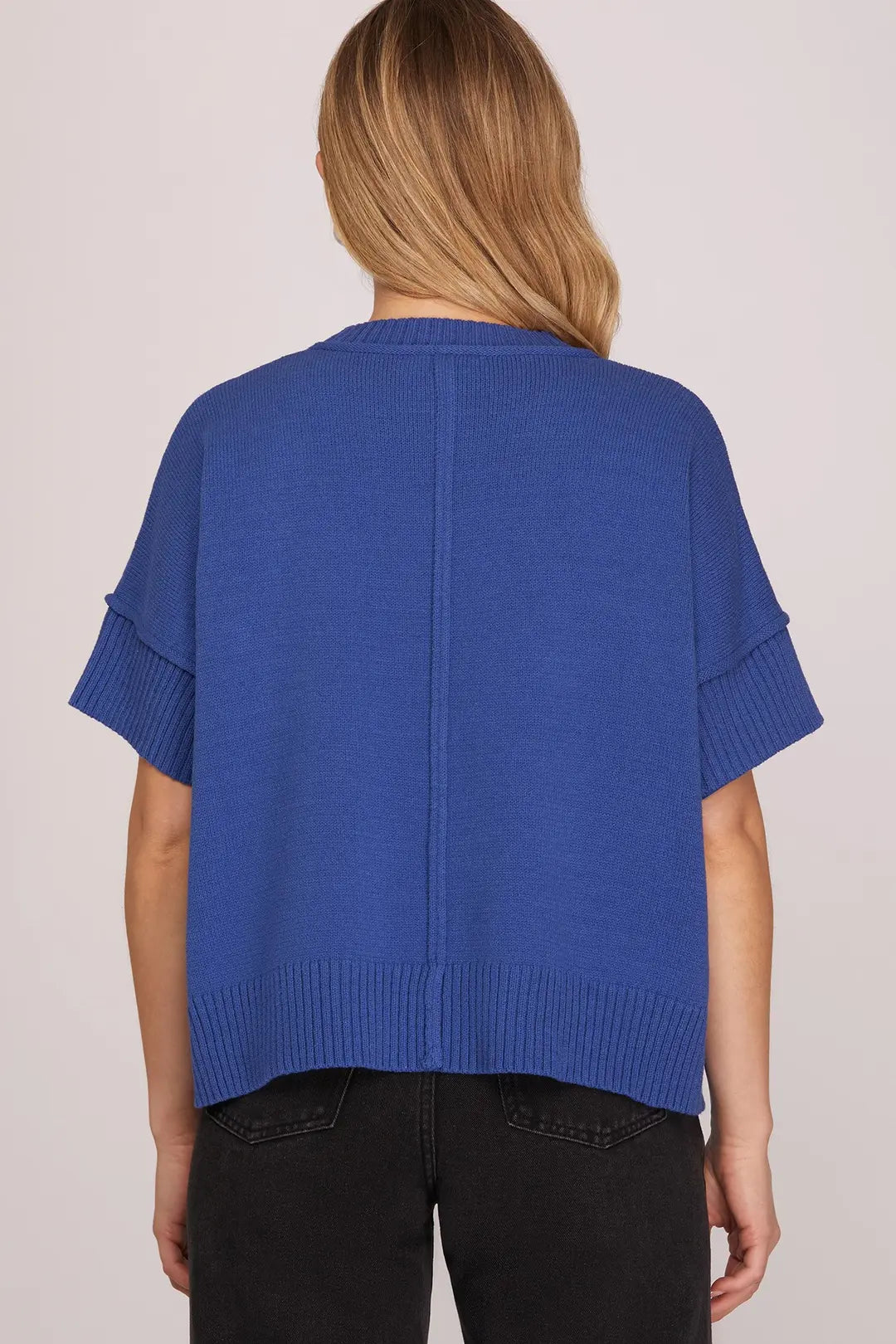 Blue knitted top worn by a person on a plain background