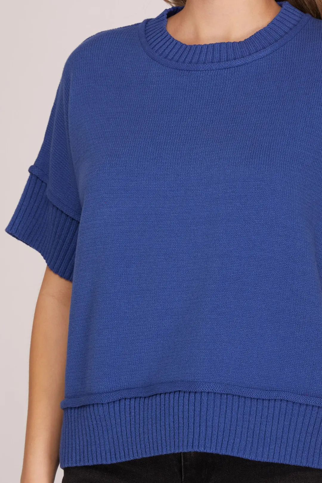 Blue knitted sweater worn by a person on a light gray background
