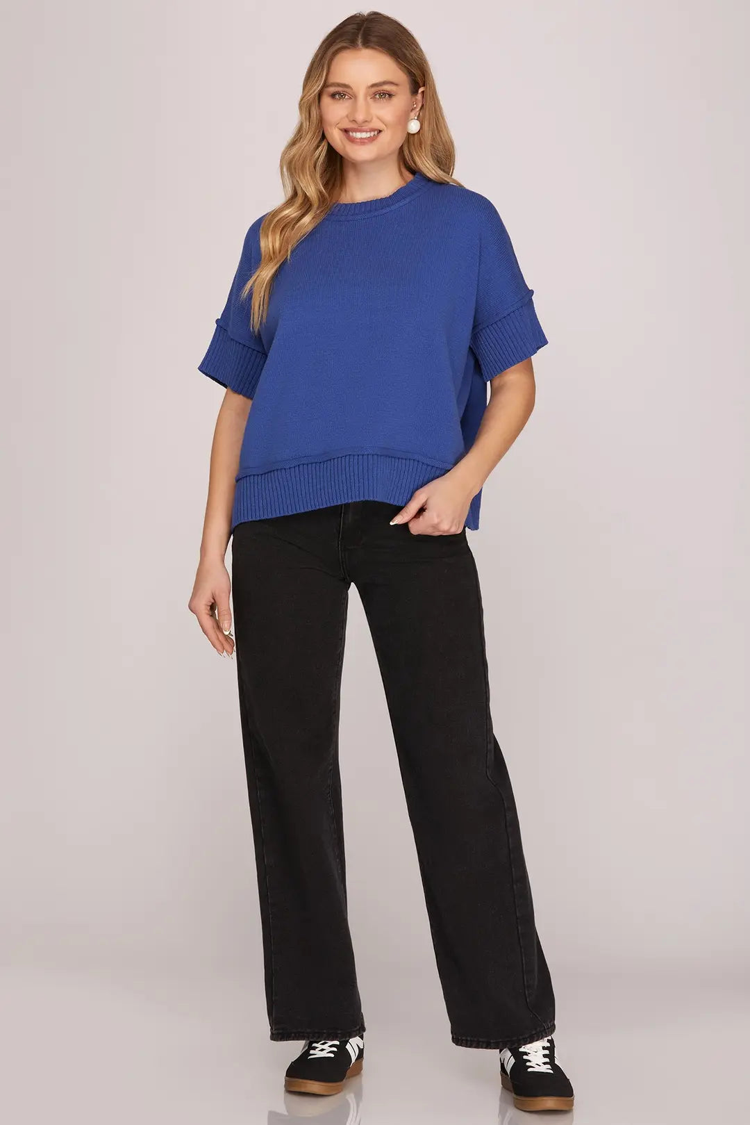 Woman wearing a blue top and black pants on a plain background