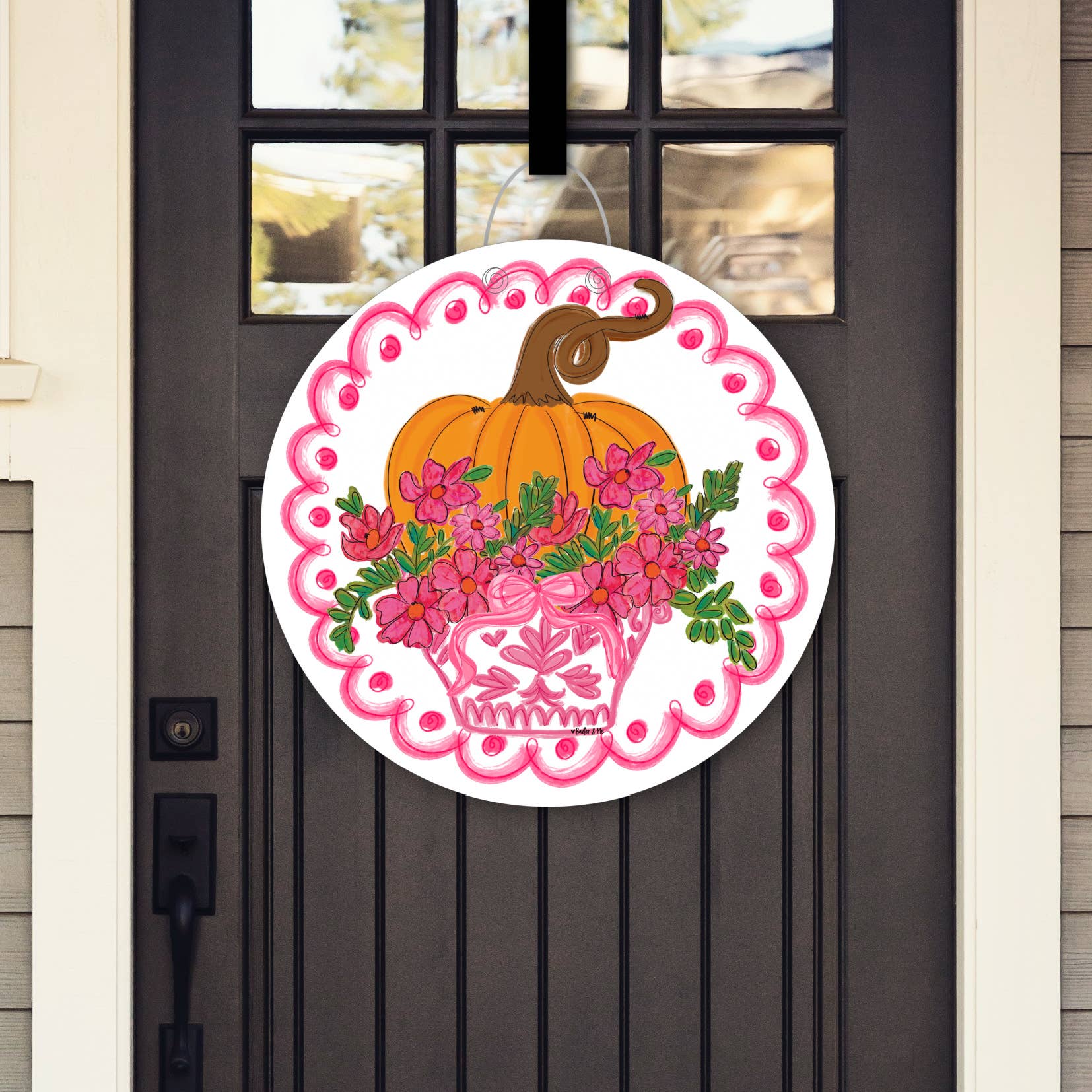 Decorative door hanger with pumpkin and floral design on a black door.