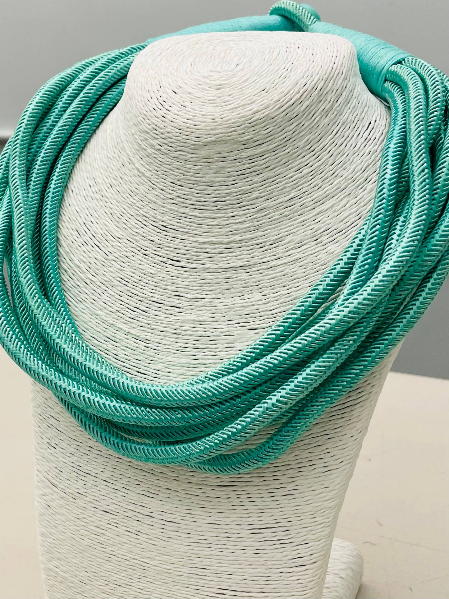 Turquoise necklace on a mannequin bust against a neutral background