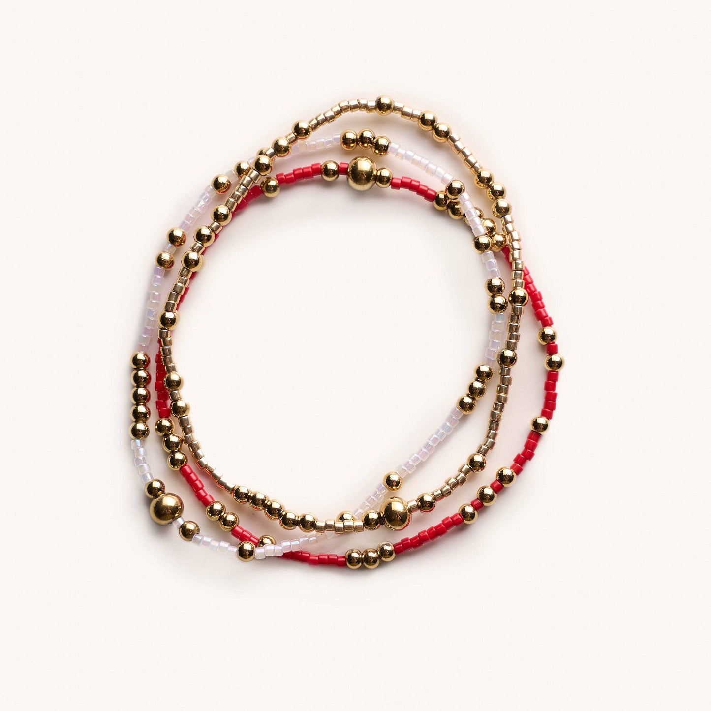 Set of three beaded bracelets with gold beads on a white background