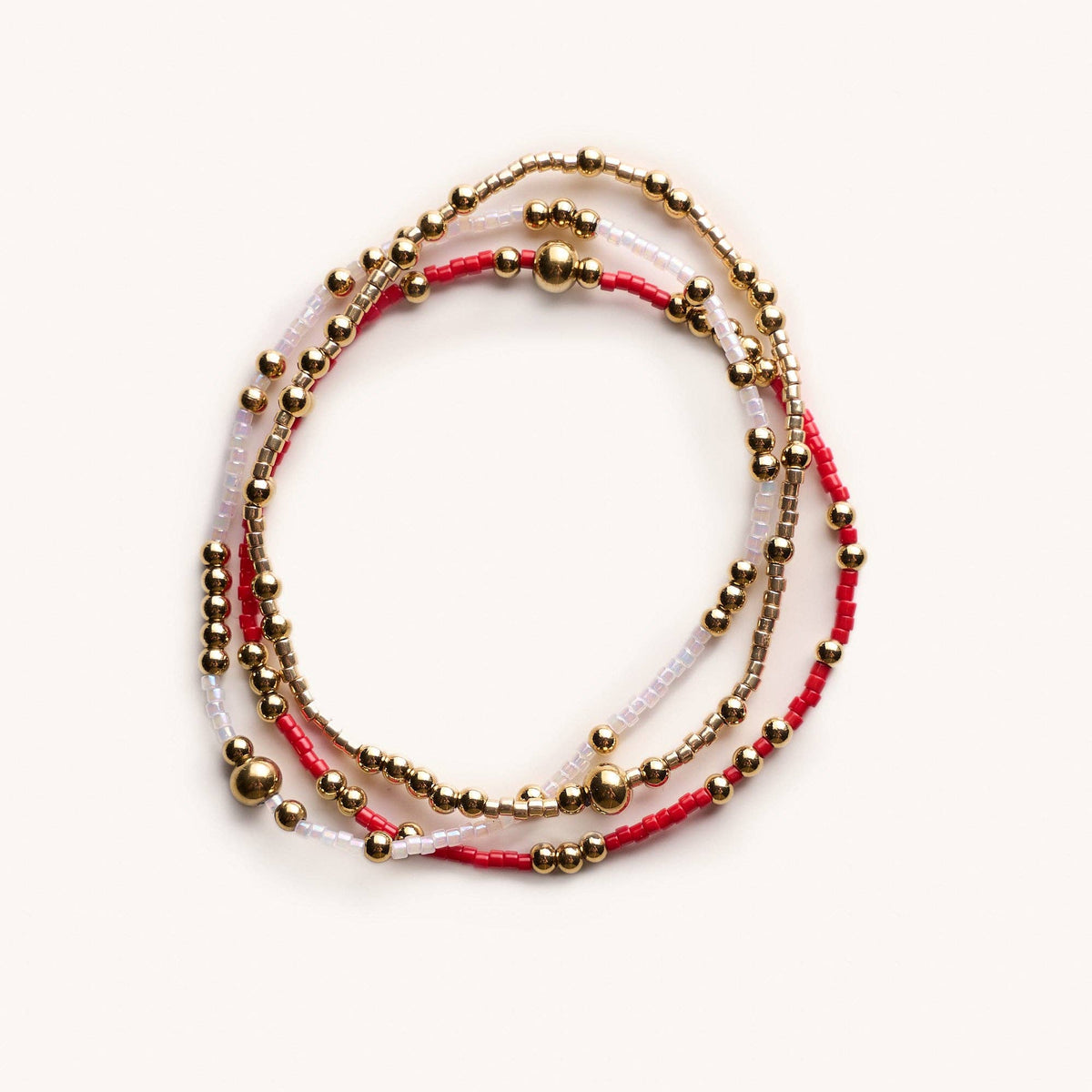 Set of three beaded bracelets with gold beads on a white background