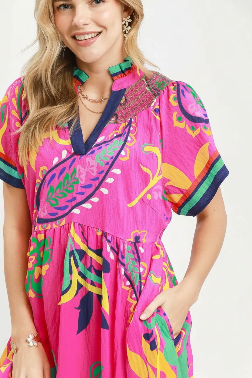 Woman wearing a colorful dress with a pink base and floral patterns on a white background