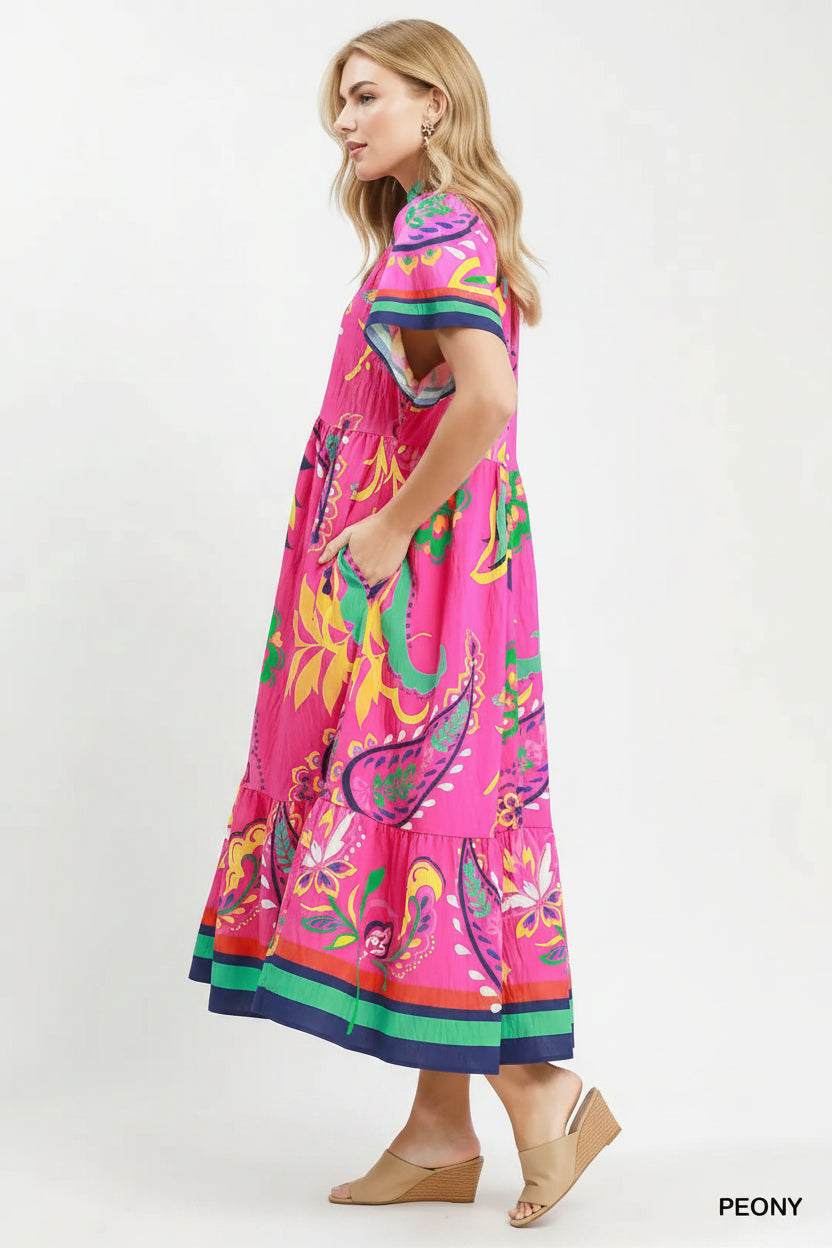 Woman wearing a colorful dress with floral pattern on a white background, featuring Umgee branding.
