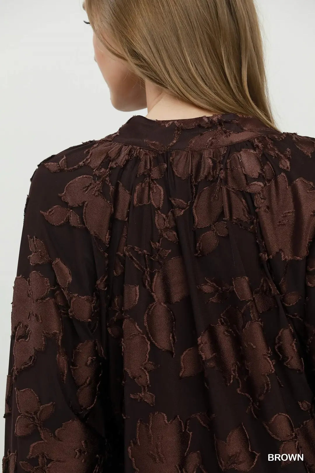 Brown floral patterned blouse on a plain background