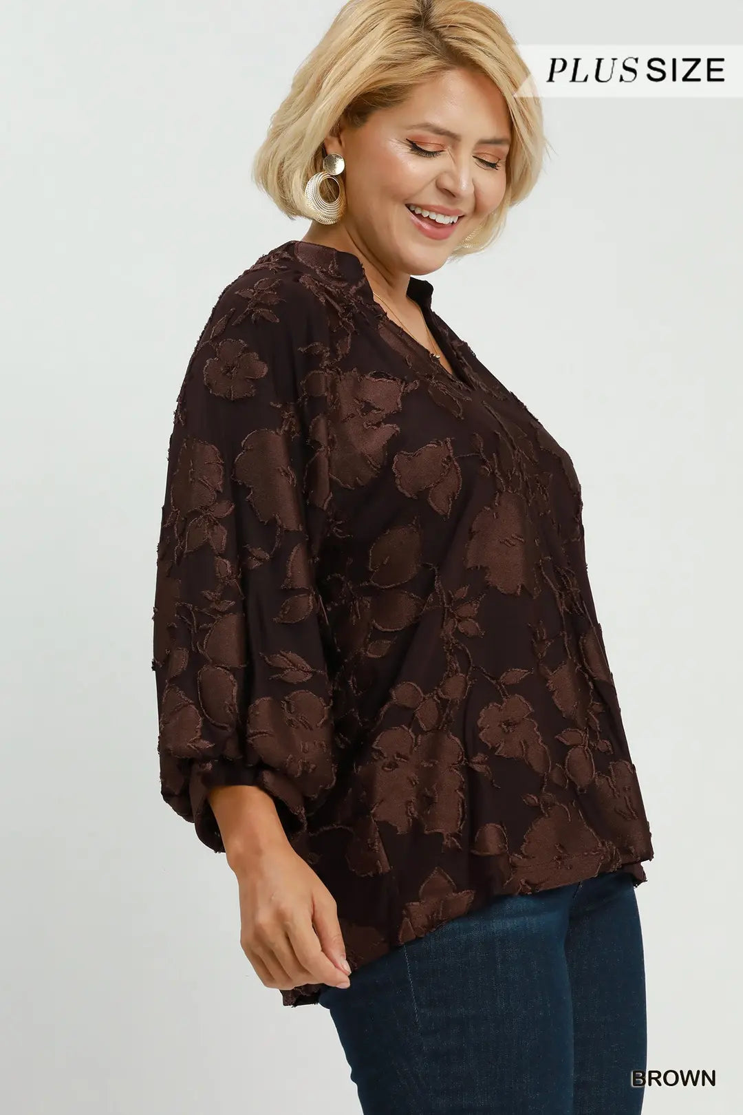 Woman wearing a brown floral blouse with text indicating 'Plus Size' and 'Brown'.