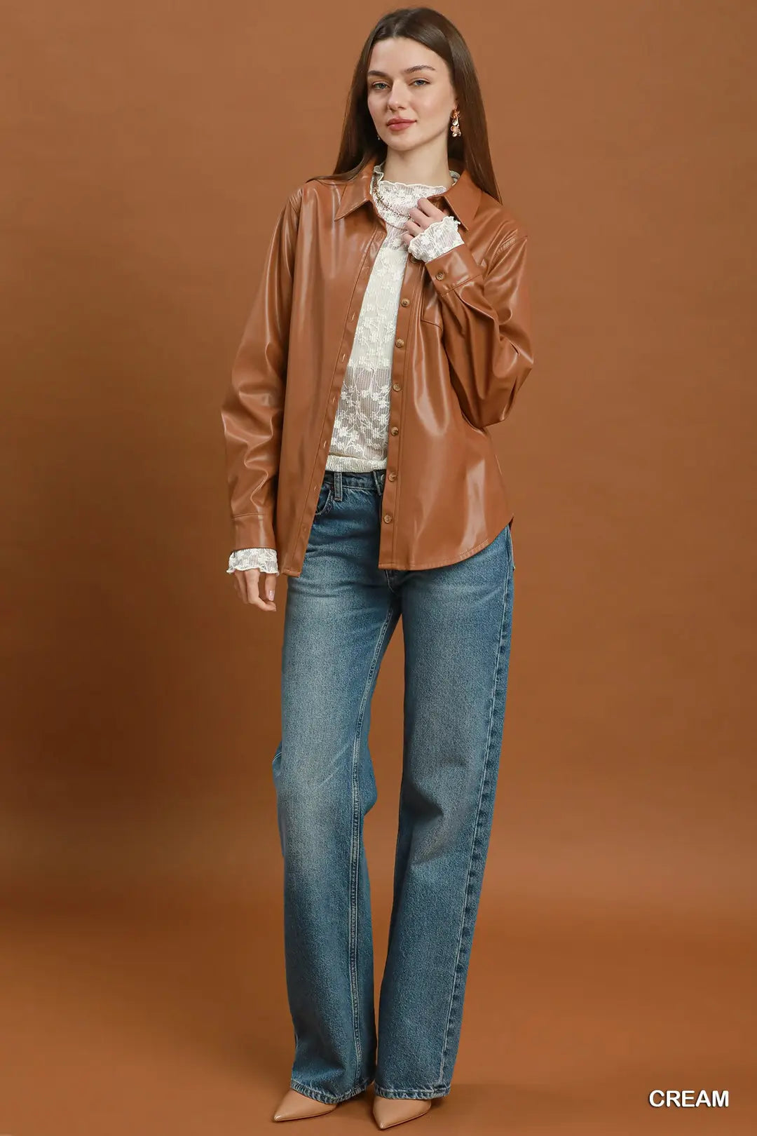 Woman wearing a brown leather jacket and blue jeans against a brown background