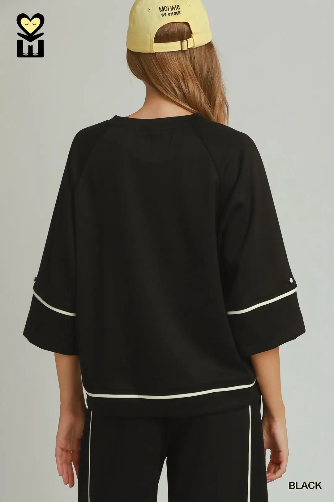 A model wearing a black umgee luxeknit top with white pipping