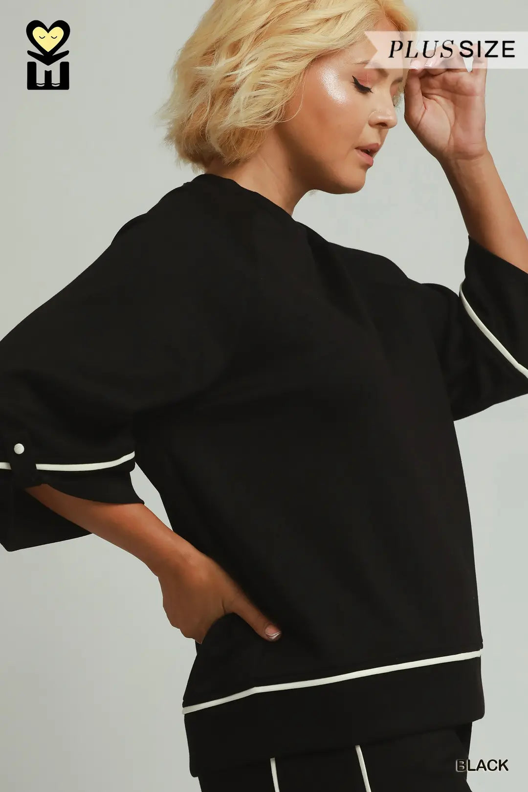 A model wearing a black umgee luxeknit top with white pipping in plus size 