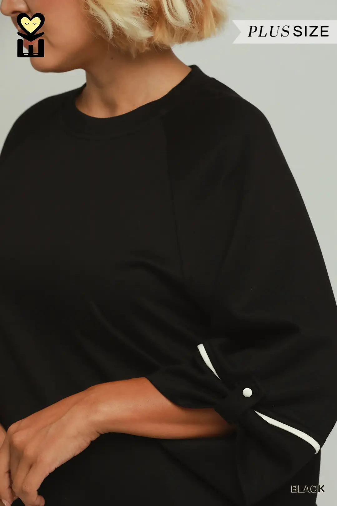 A model wearing a black umgee luxeknit top with white pipping in plus