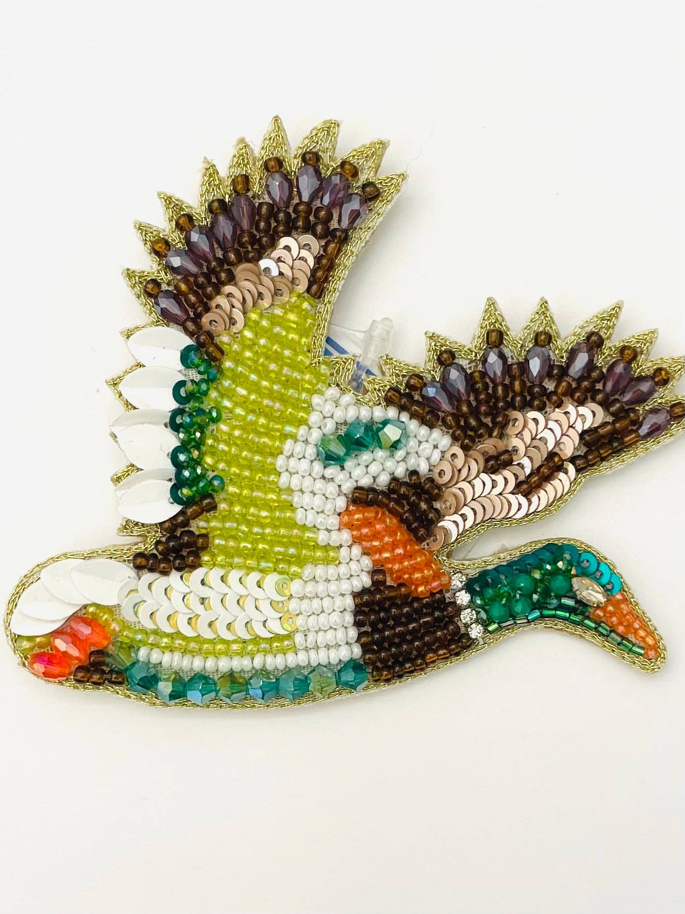 A hand-beaded decorative bird ornament, likely a duck, crafted with multicolored seed beads, sequins, and metallic trim on a plain white background.