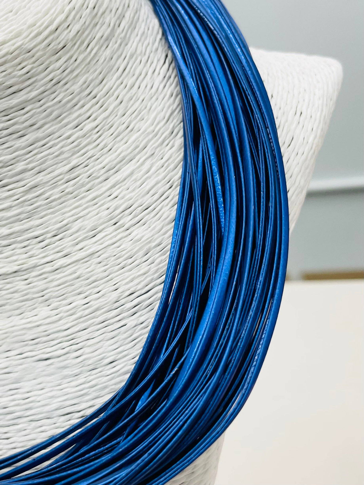 Close-up of a white straw hat with blue ribbon on a light gray background