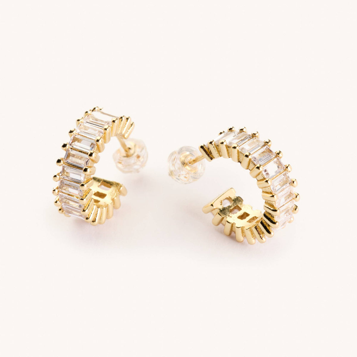 Gold hoop earrings with clear gemstones on a white background