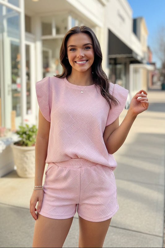 Woman wearing a pink outfit standing outdoors with a building in the background