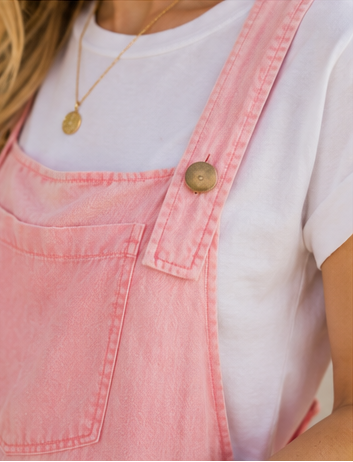 Person wearing a pink denim apron over a white shirt with a blurred background