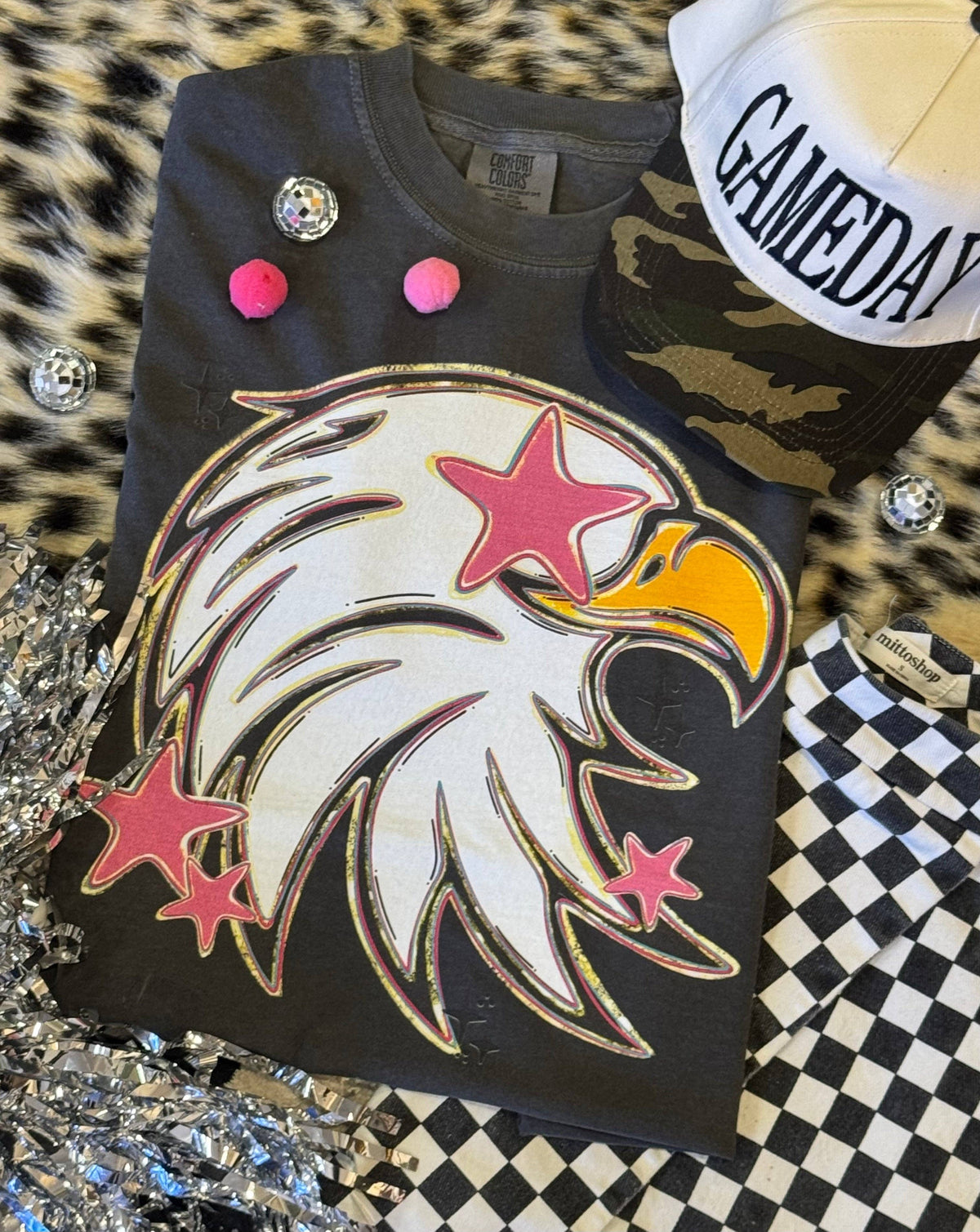 Black shirt with eagle design and colorful buttons on a checkered surface