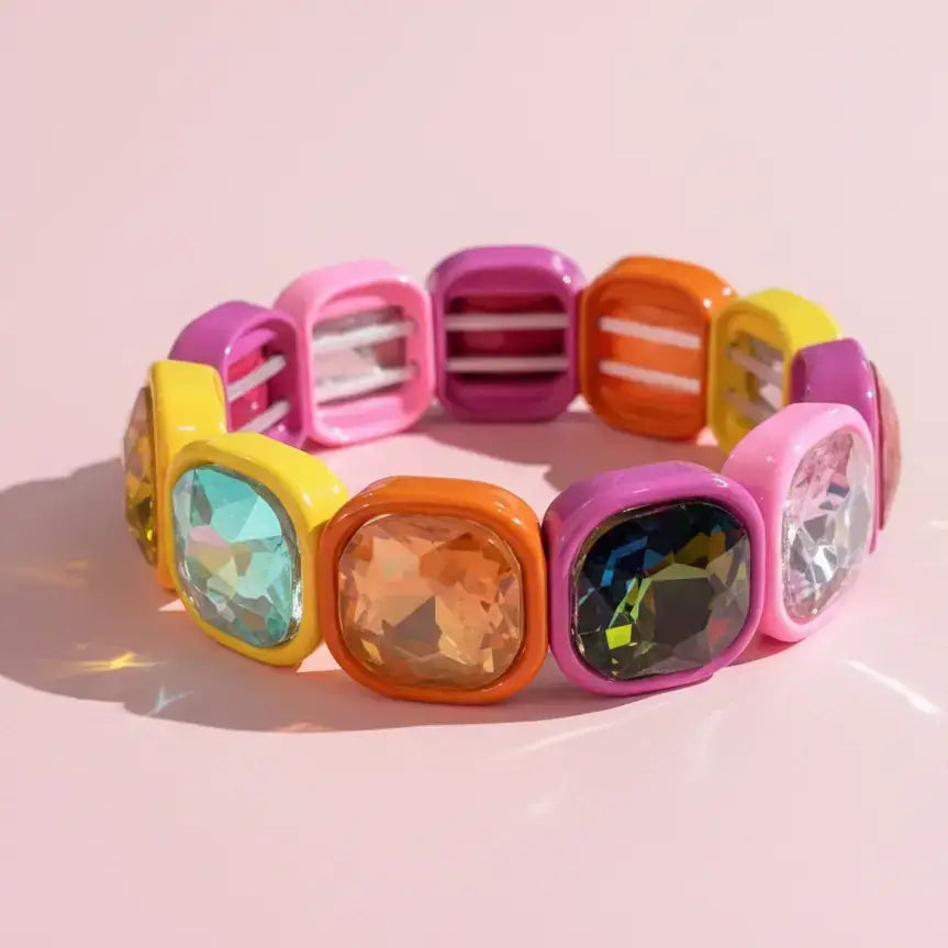 Colorful bracelet with transparent gemstones on a pink background