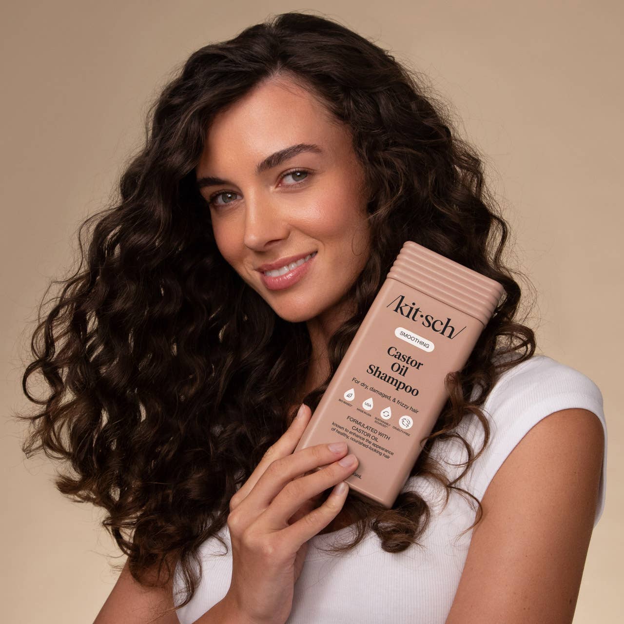Woman holding Kitsch Smoothing Castor Oil Shampoo bottle