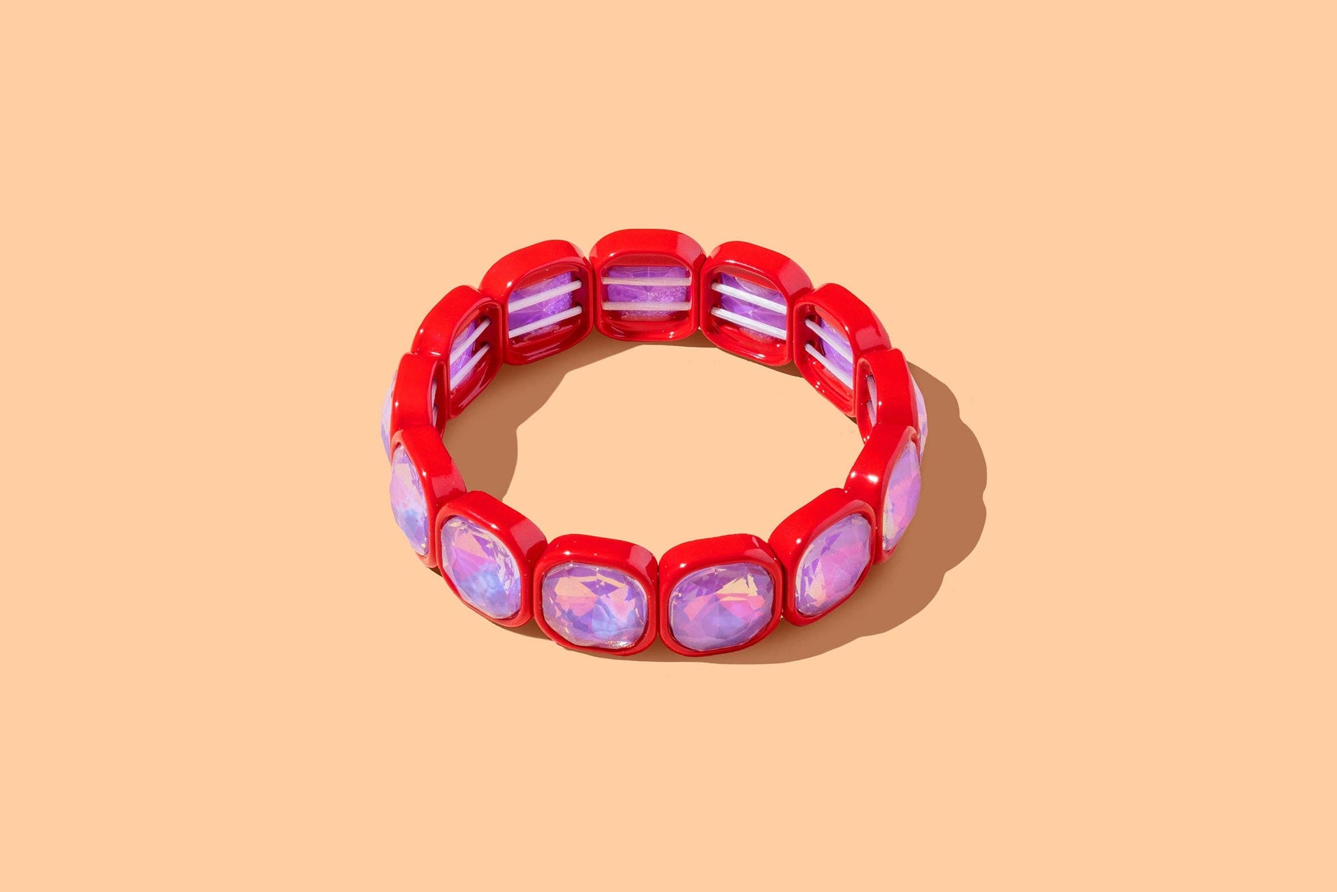 Red bracelet with pink gemstones on a beige background