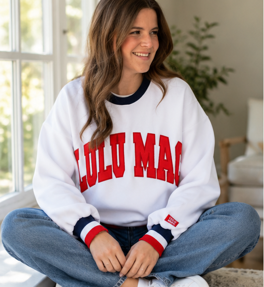 Woman wearing a white sweatshirt with 'LULu MAC' text, sitting on a couch, and standing outdoors.