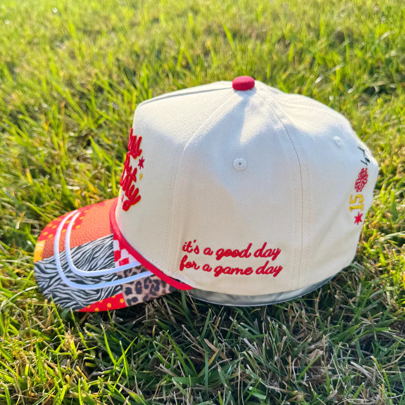 Baseball cap with 'it's a good day for a game day' text on grass