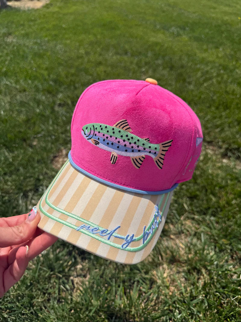 Pink cap with fish design held in front of a grassy background