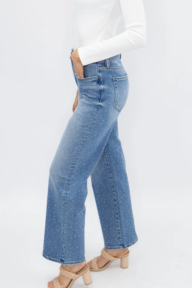 Woman wearing high rise rhinestone straight leg jeans with sparkling embellished denim and a relaxed fit.